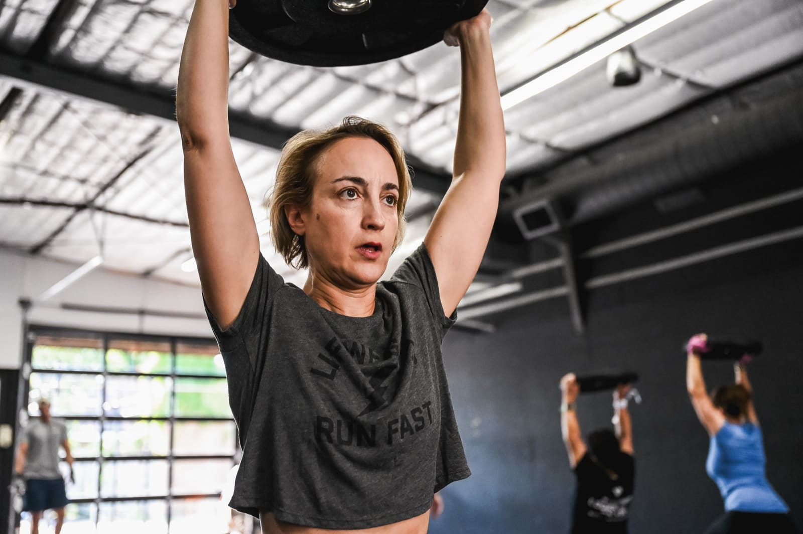 small group training session at District H in Houston Heights, member lifting barbell overhead