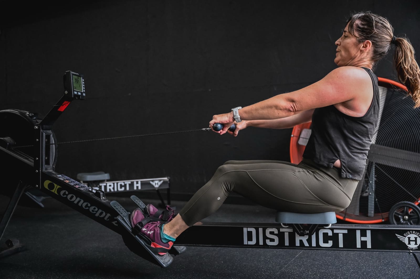 member rowing on a branded District H Concept2 rower during a personal training session