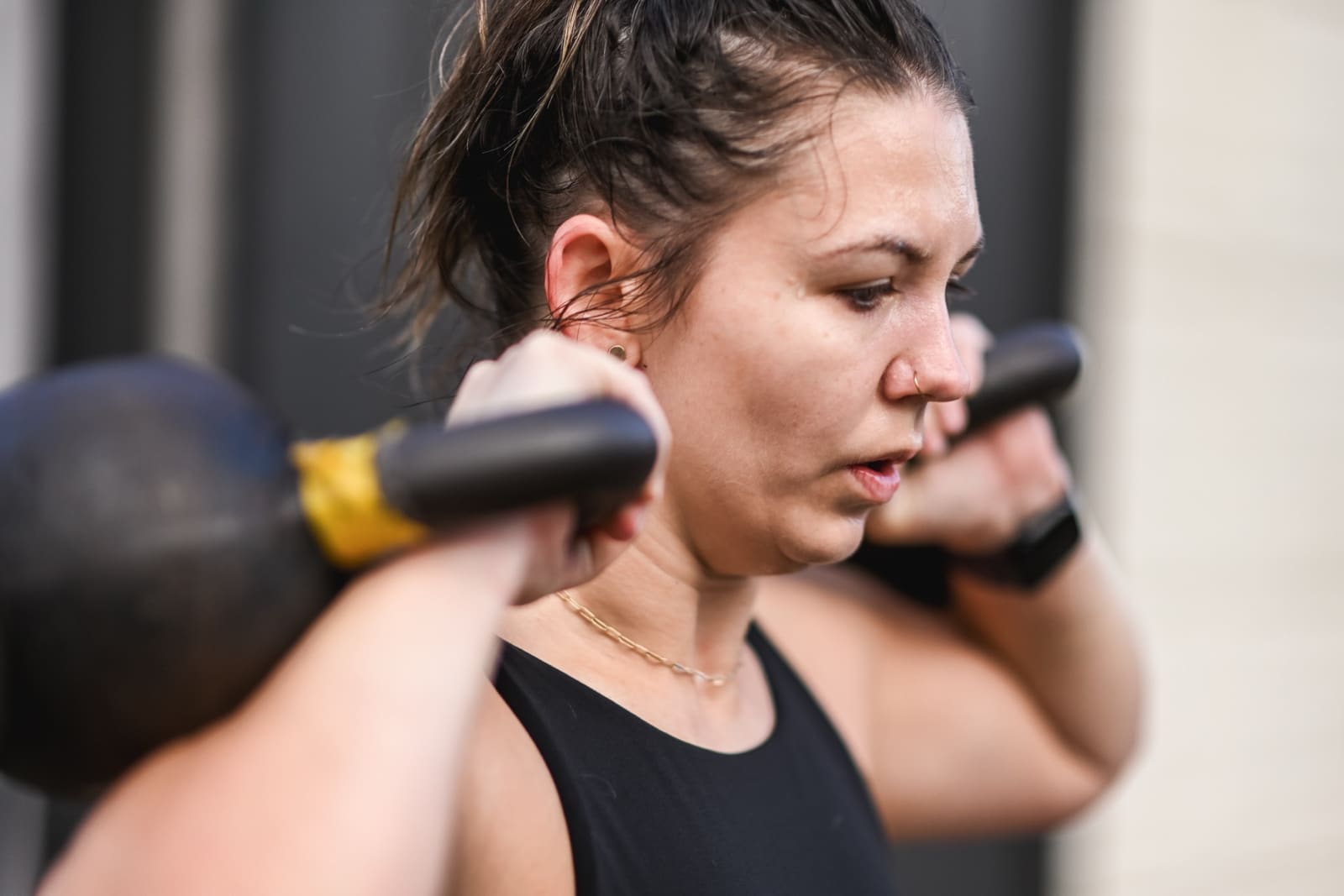 member pressing dual kettlebells during a small group training session at District H Heights